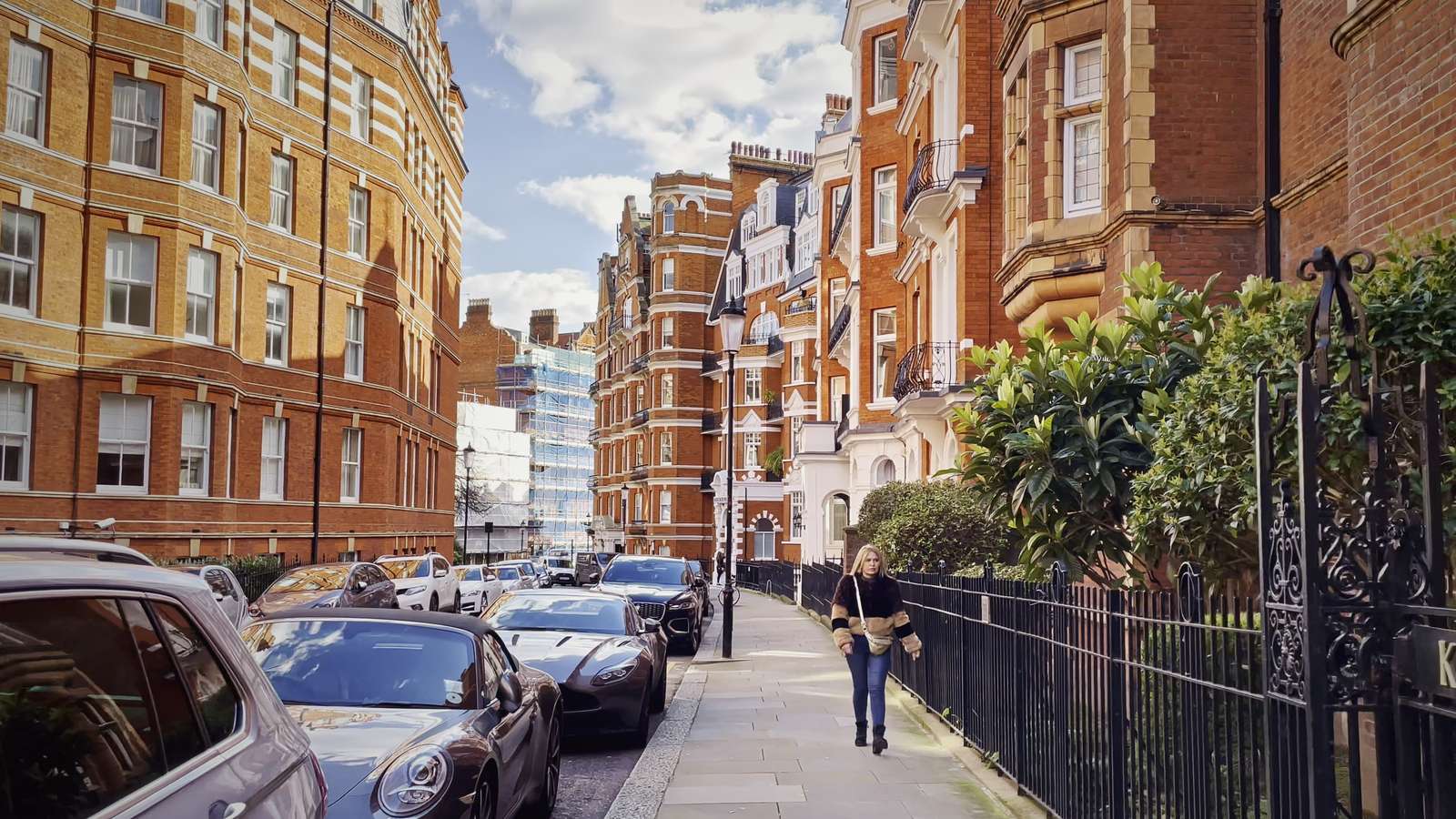 A quiet red-brick mansion-block street in west London in soft afternoon light.