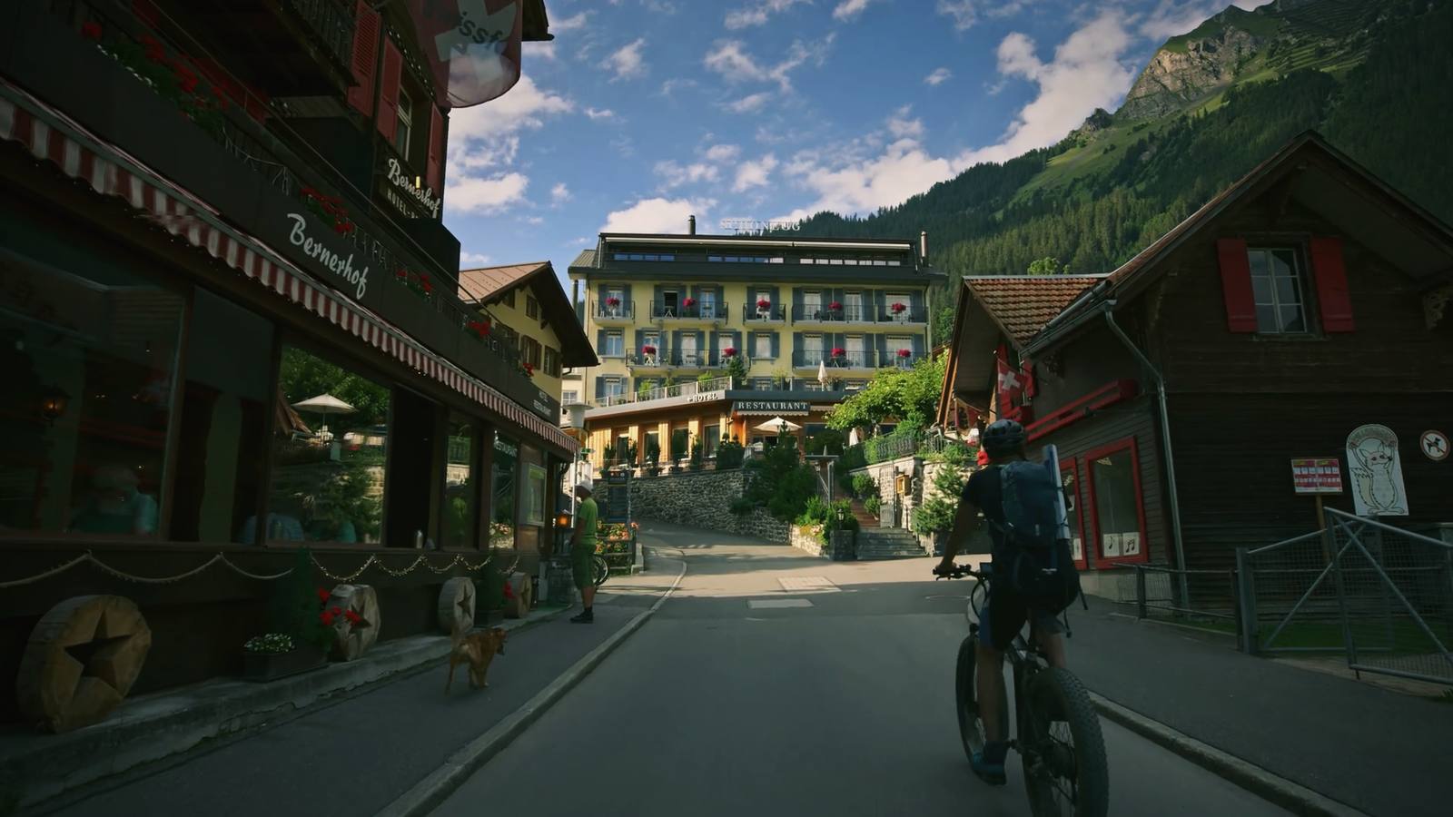 A cyclist riding through a Swiss mountain village on a summer afternoon.
