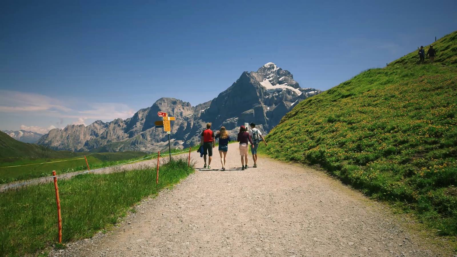 A small group walking together along a mountain trail in the Swiss Alps.