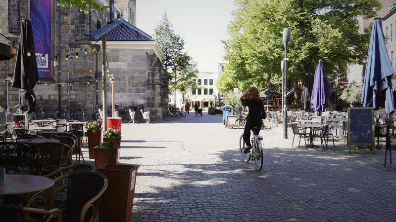 A calm church square in a Dutch old town, with a cyclist crossing.