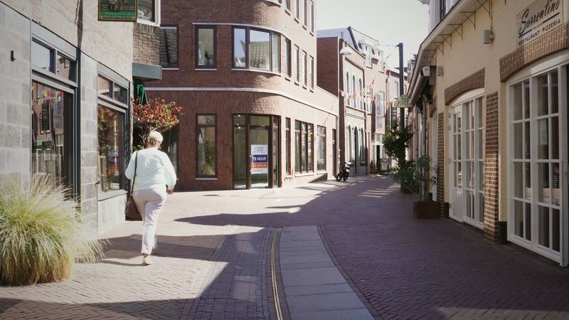 A traveller walking down a quiet, sunlit European lane.